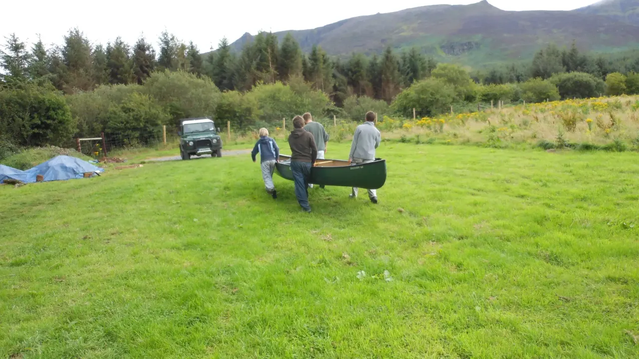 Boys carrying canoe in field