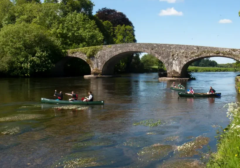 canoes on river with 3 arch bridge